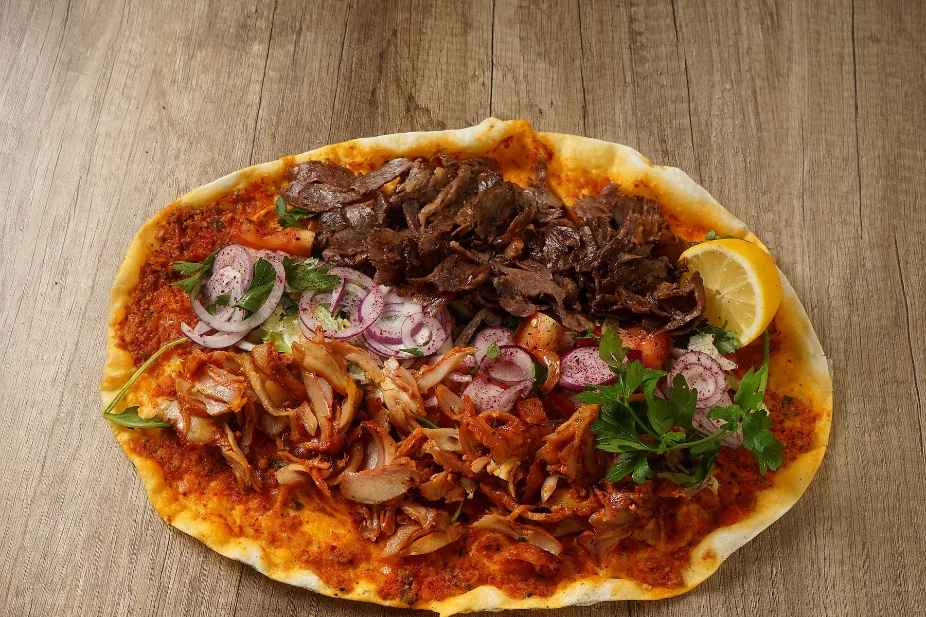 Türkische Pizza mit Fleisch, Salat und Zitrone
